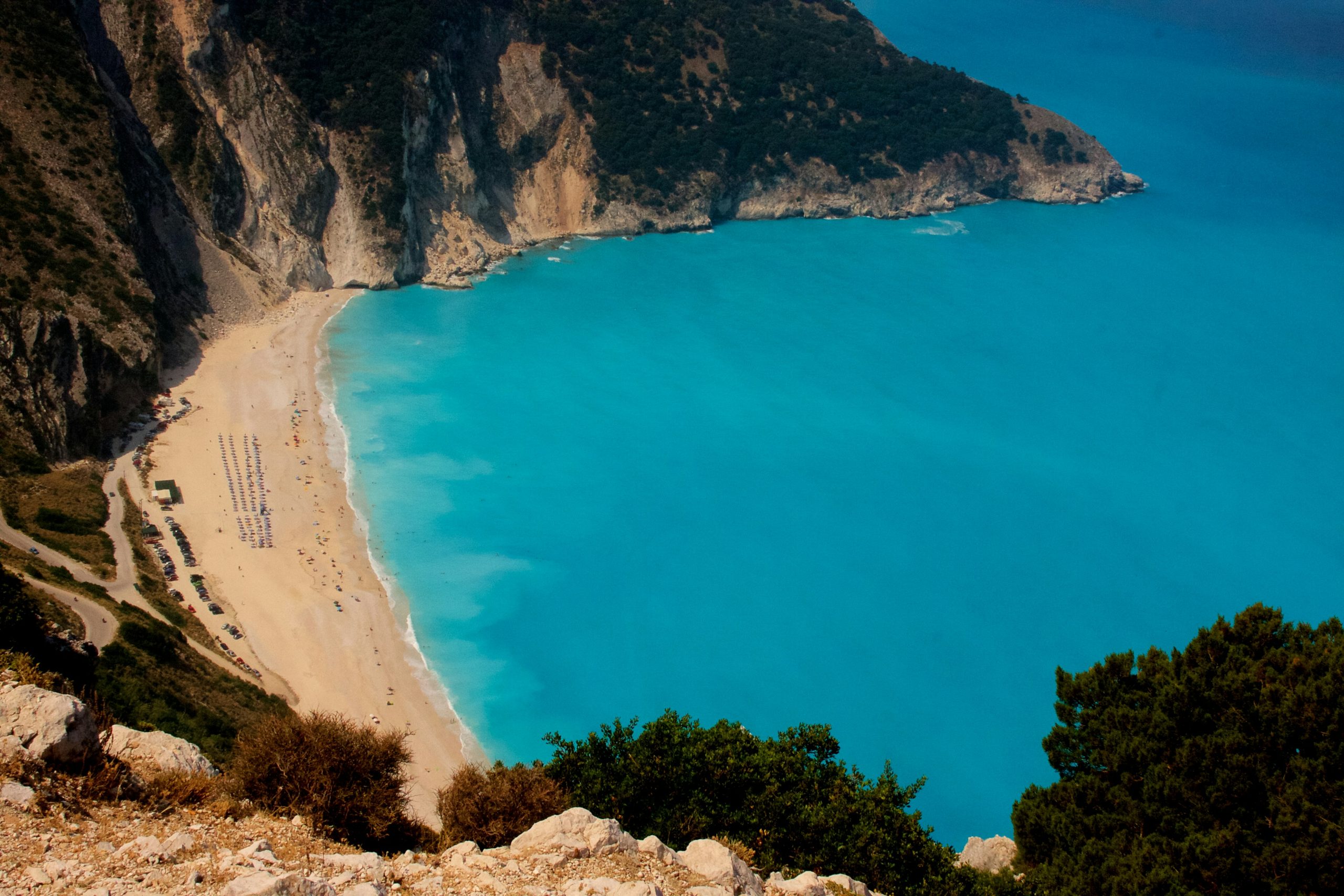 grcka-kefalonija-plaza-myrtos-turistina-plazi-plava-voda-planine-okolo-suma