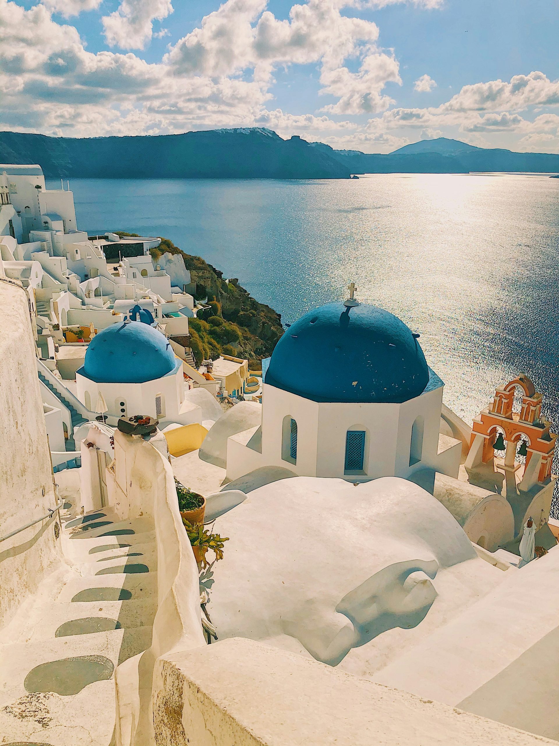 grcka-santorini-bele-kuce-plavi-krov-more-okolo-crne-planine-plavo-nebo